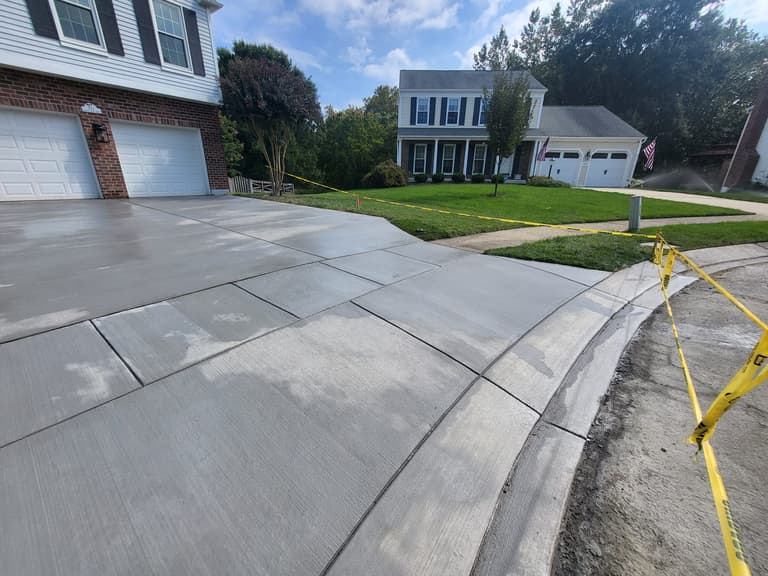 The curved edge of the new driveway where it meets the lawn and the street