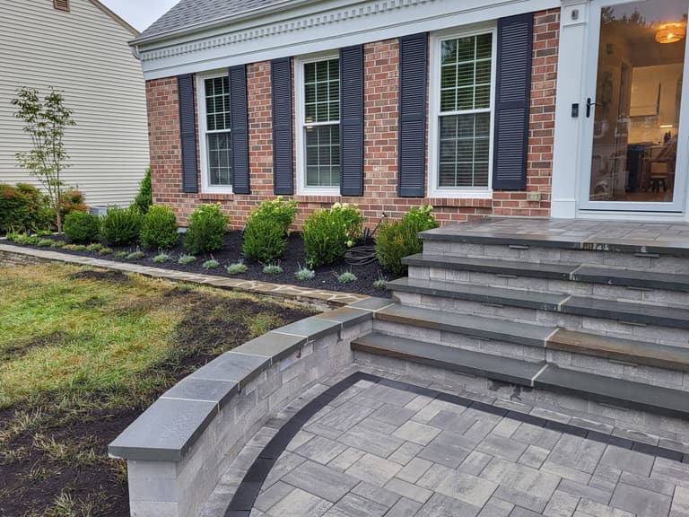 Charcoal large-format paver landing and steps behind a curved seat wall at a brick colonial in Annapolis