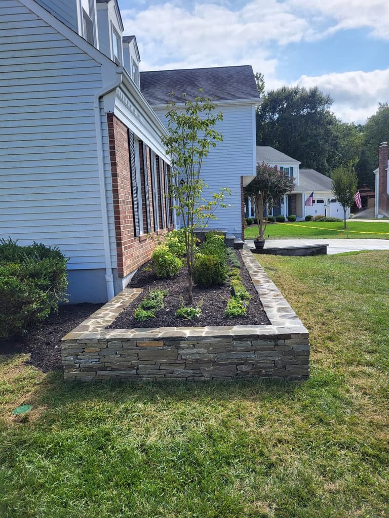 The stacked-stone planter wall and its new plantings running along the side of the house