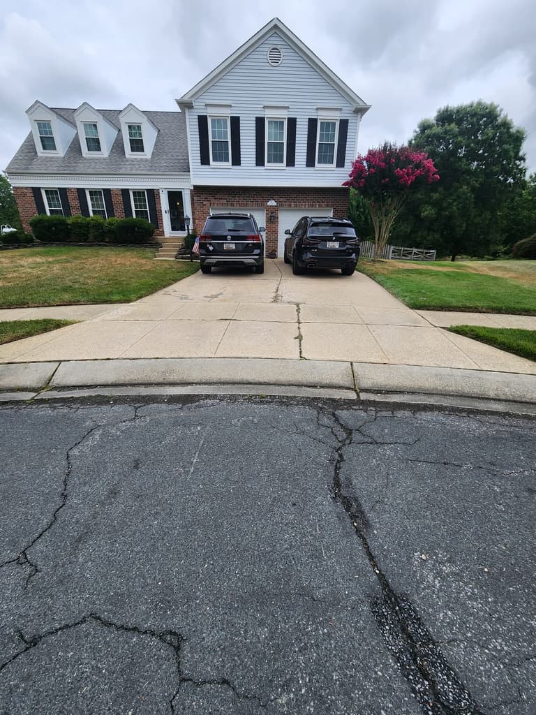 Before — the cracked and patched concrete driveway seen from the street