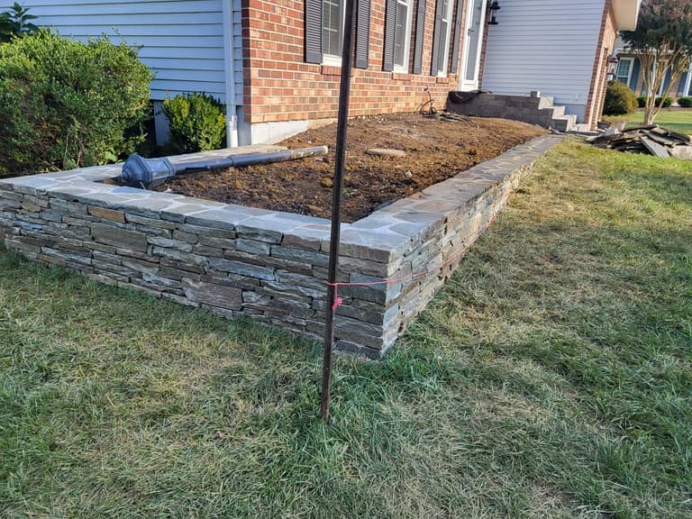 During — the stacked-stone planter wall built up along the front of the house, bed excavated behind it