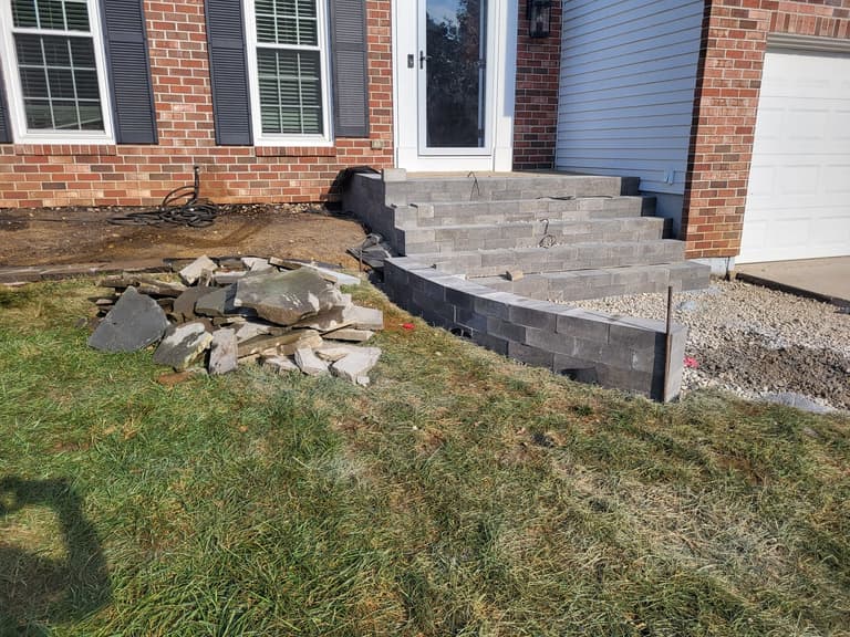During — the new block steps set and the curved wall taking shape, with flagstone stacked alongside
