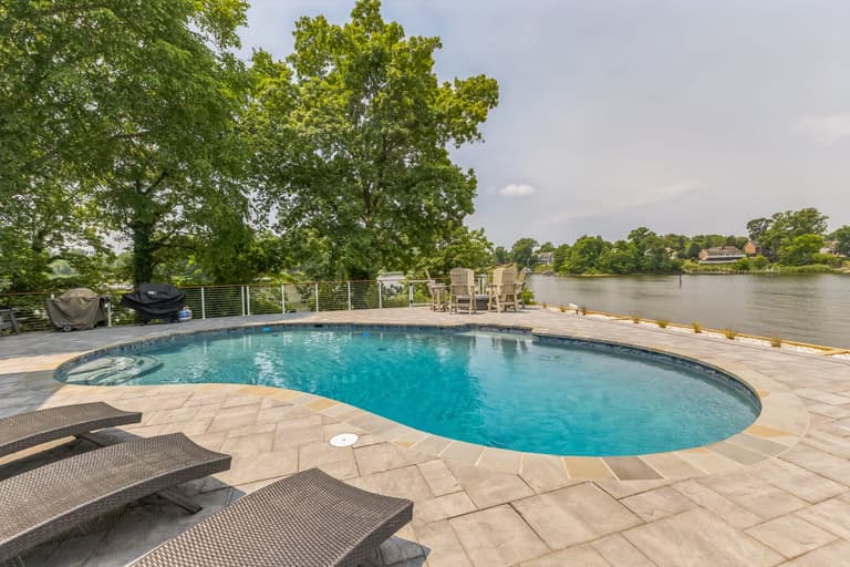 Loungers along the paver deck with the water behind the pool