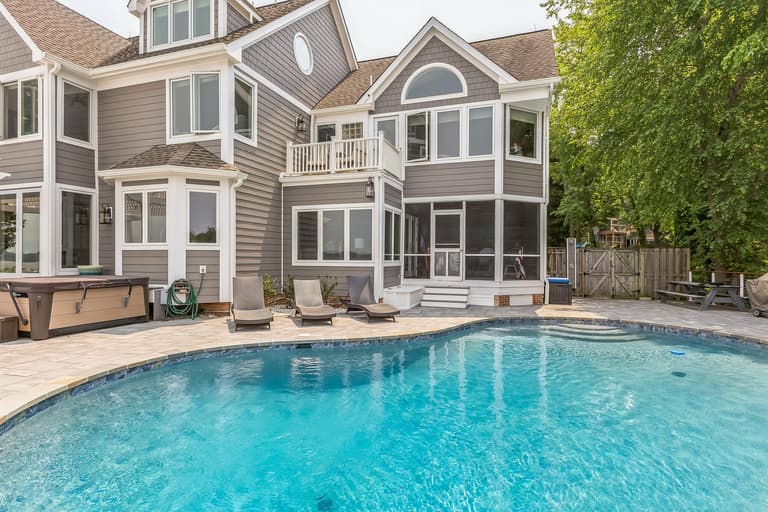 Spa set into the paver pool deck against the rear of a waterfront home in Arnold