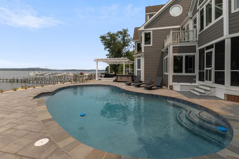The pool deck and terrace with the house on one side and the shoreline on the other