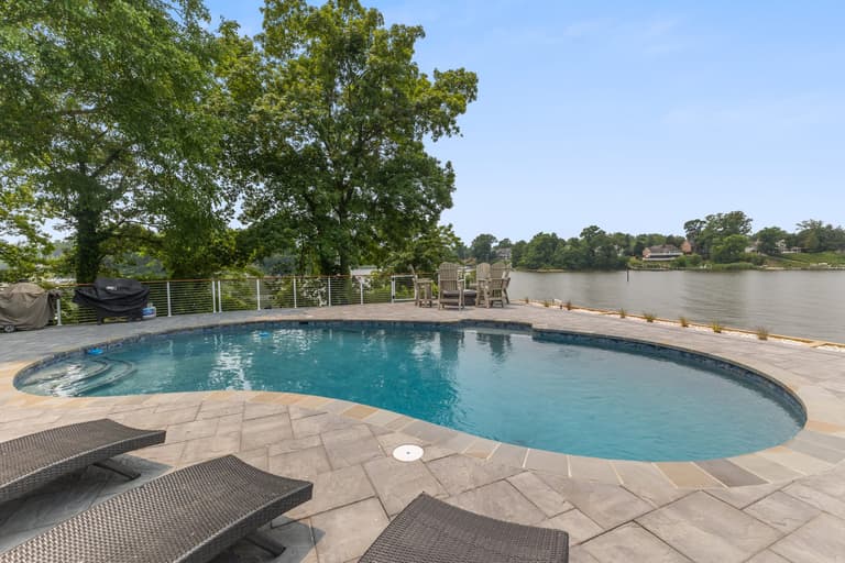 Wide view of the freeform pool and paver deck against the open water