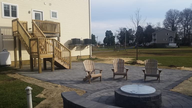 Paver patio with Adirondack chairs around a fire pit