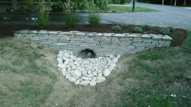 Stacked-stone headwall around a culvert with a river-rock apron