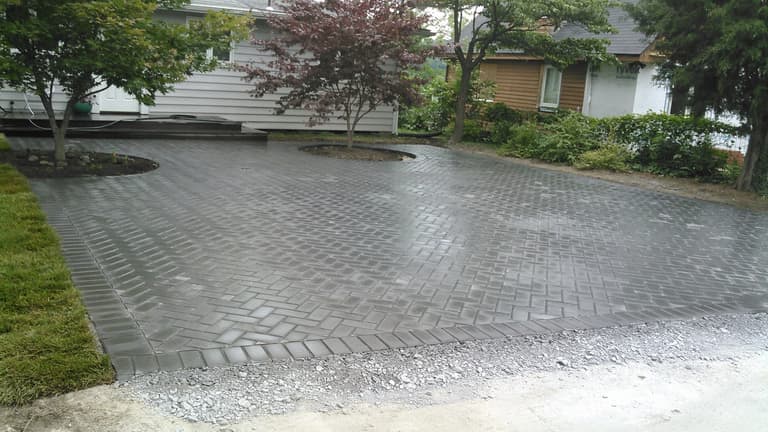 Herringbone paver driveway with a soldier-course border and planted islands in Riva