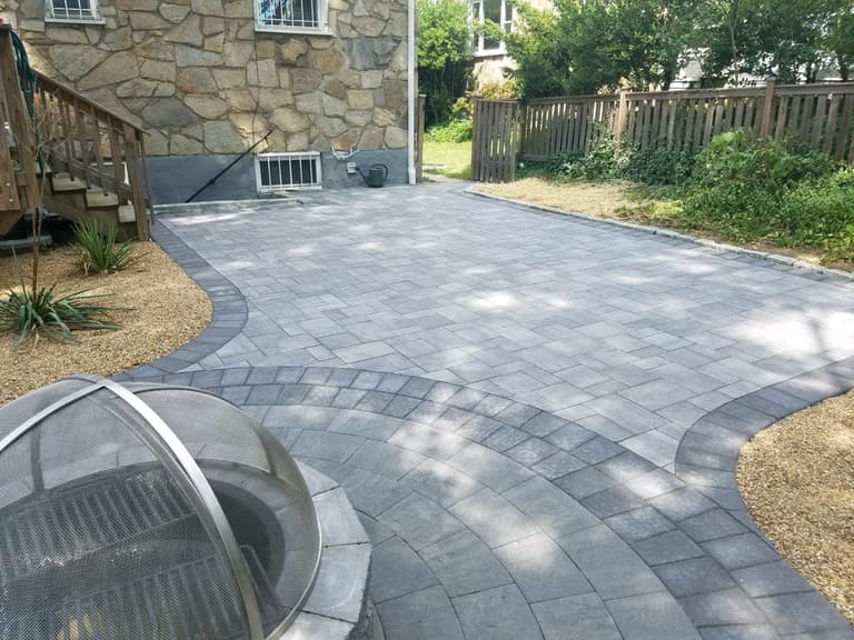 Grey paver landing with a fire pit, curved seat wall, and stone steps