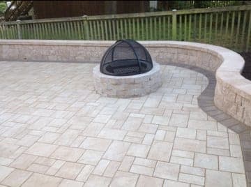 Cream paver patio with a curved seat wall and fire pit
