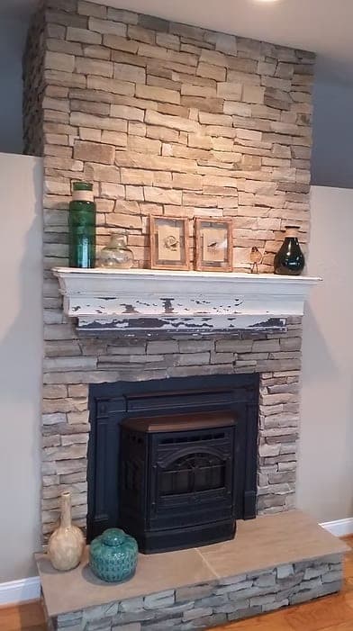 Stone-veneer fireplace surround with a painted mantel and a cast-iron insert