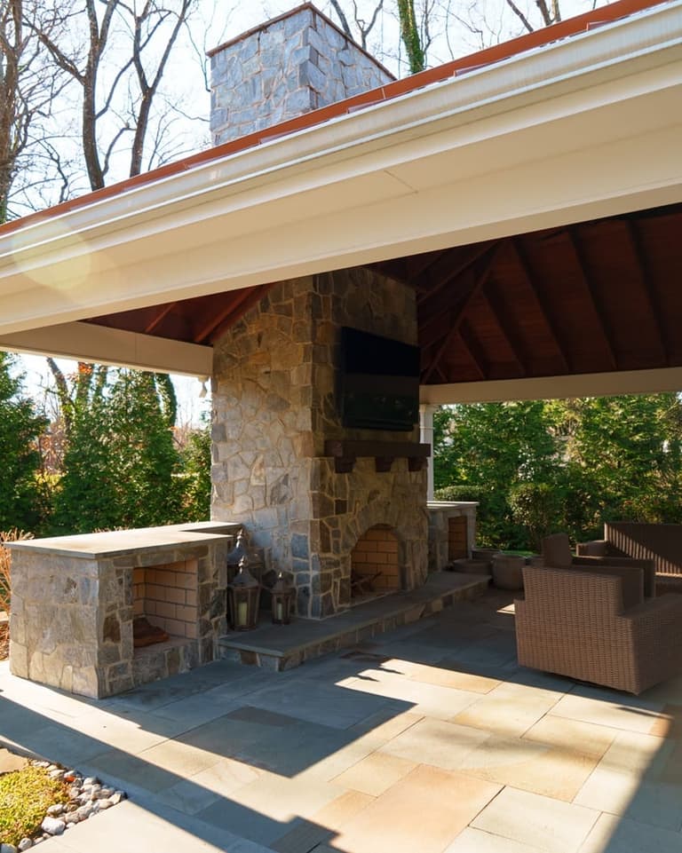 Covered pavilion with a full stone outdoor fireplace, wood storage, and a flagstone floor