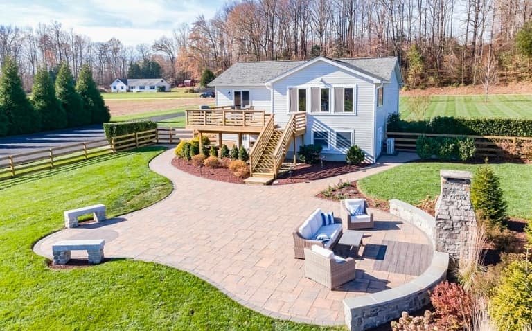 Rear patio, deck and mulched planting beds framed by a maintained lawn