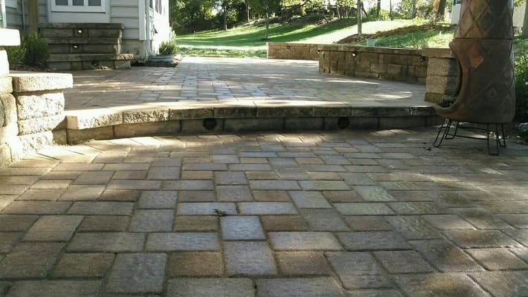 Large-format paver patio with broad steps up to a lawn