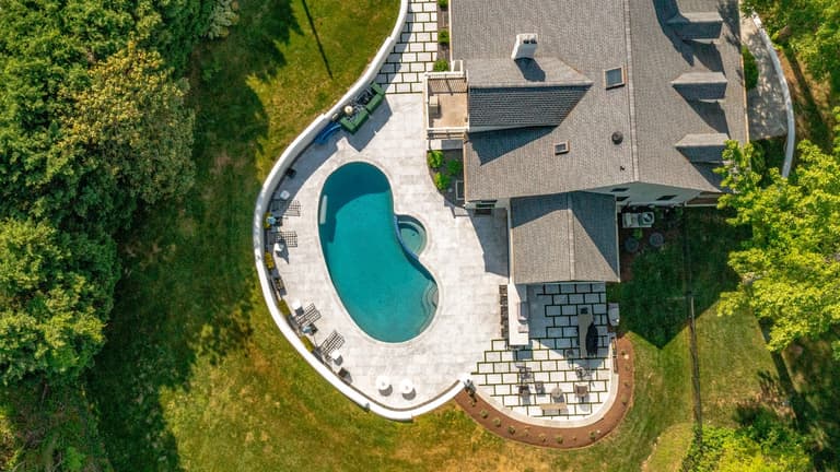 Aerial view of a paver pool deck wrapping around a home