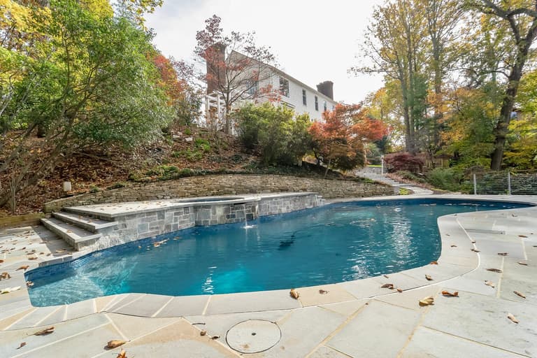Flagstone pool deck with a glass railing in autumn