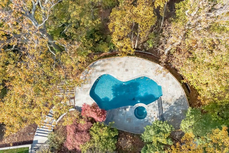 Aerial view of a flagstone pool deck and freeform pool in autumn
