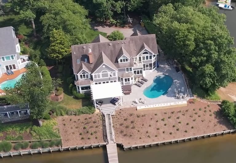 Aerial view of a waterfront estate pool and paver deck