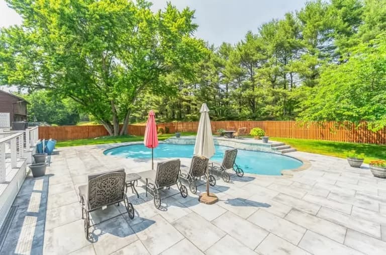 Freeform pool with an attached spa and paver deck