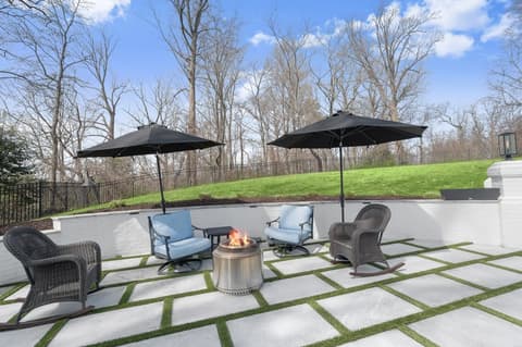 Sandblasted marble patio with artificial turf inlays and lounge seating against a white brick seat wall