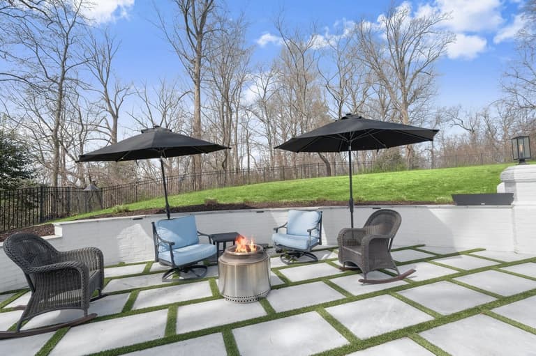 Sandblasted marble patio with artificial turf inlays and lounge seating against a white brick seat wall