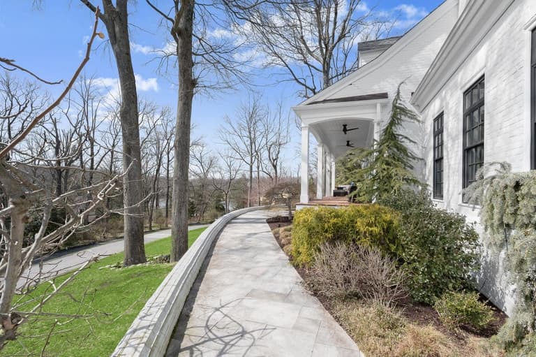 Sandblasted marble walkway curving along the home above a white brick retaining wall