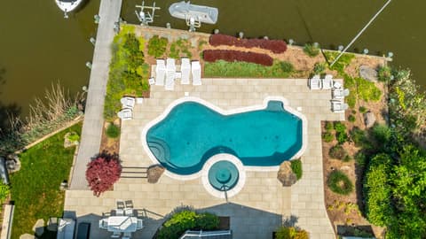 Aerial view of the waterfront pool, paver deck, and plantings