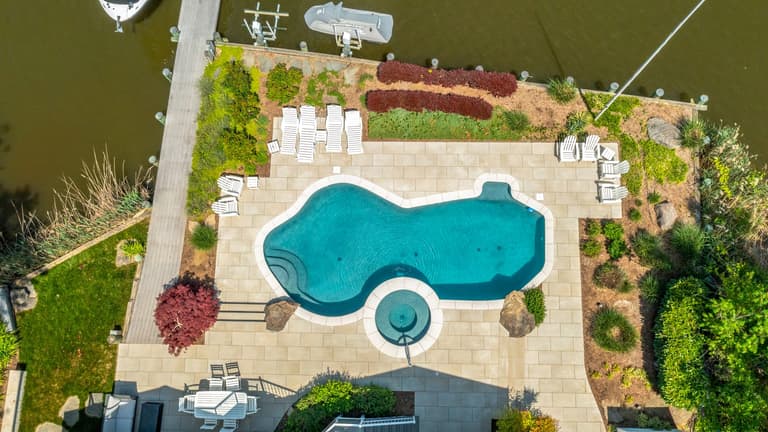 Aerial view of the waterfront pool, paver deck, and plantings