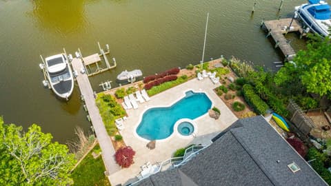 Waterfront pool and paver deck with a dock beyond