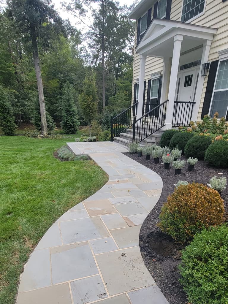 Curved bluestone walkway leading across the lawn to a covered front porch