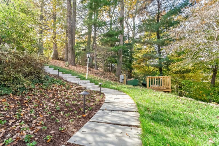 Stone path stepping down a wooded hillside, lit by low-voltage path lights